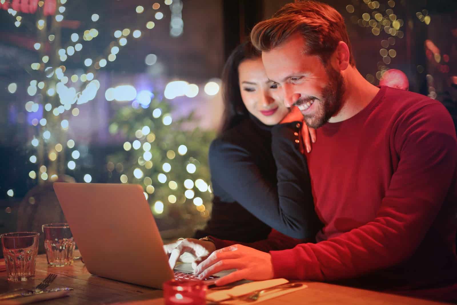 man och kvinna tittar på silver laptop medan le
